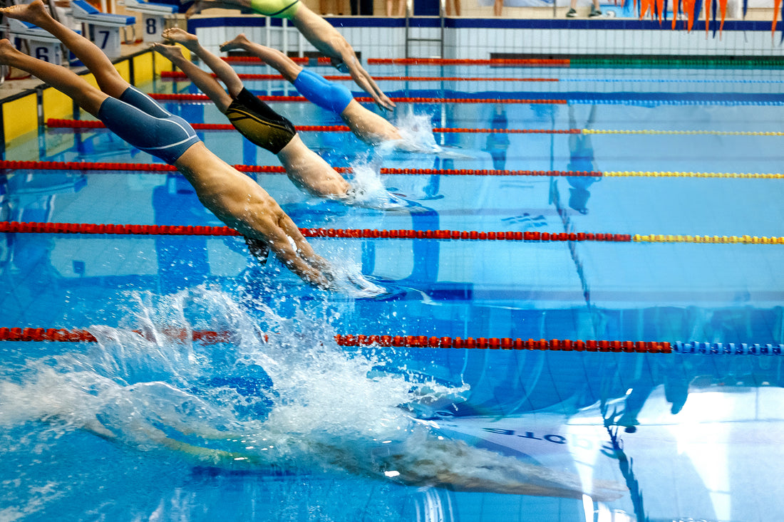 Group of male athletes and swimmers diving at the starting line